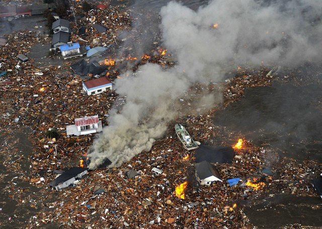 Flames rise from houses and debris half submerged in tsunami in Sendai, Miyagi Prefecture (state) after Japan was struck by a strong earthquake off its northeastern coast Friday, March 11, 2011.